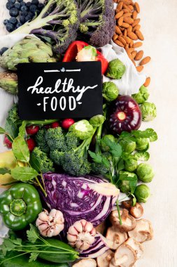 Hafif ahşap arka planda sebzeli masa. Biber, lahana, brokoli, turp, sarımsak. Sağlıklı beslenme konsepti. Üst görünüm