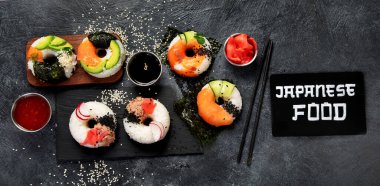 Sushi donuts on a dark background. Hybrid trend food. Top view, banner clipart