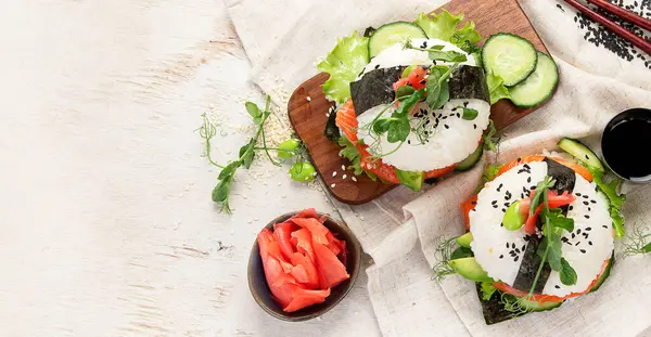 Hybrid modern food. Sushi burger with salmon, white rice, avocado, cucumber. Top view, copy space, banner