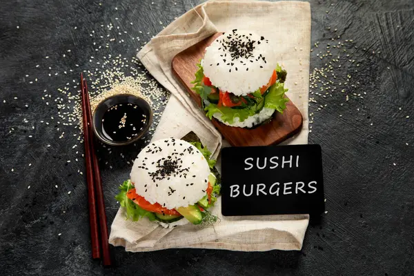 アジアの寿司バーガー 暗い背景にチョップスティック トレンドのハイブリッド食品 トップビュー — ストック写真