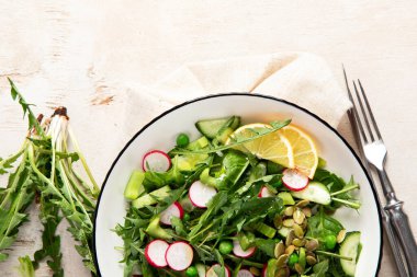 Karahindiba yapraklı bahar vejetaryen salatası, turp, ahşap kaplama salatalık. Üst görünüm, alanı kopyala