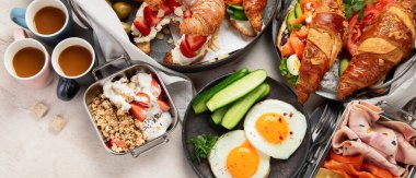 Kahvaltının yanında kahve, kruvasan, yumurta ve beyaz arka planda aperatifler var. Dengeli diyet. Üst Manzara. Panorama.