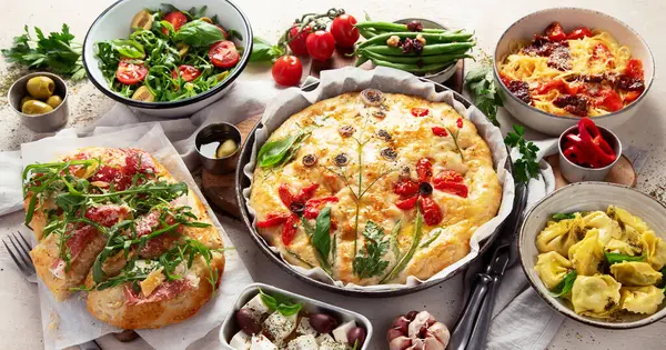 Tisch Mit Italienischen Gerichten Pizza Pasta Ravioli Focaccia Auf Weißem lizenzfreie Stockfotos