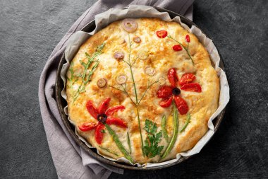 Çiçekli Focaccia, domatesli, soğanlı ve koyu arkaplanda maydanozlu İtalyan ekmekleri. Üst görünüm. 