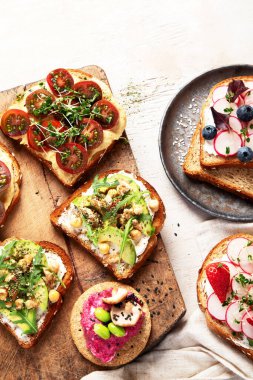 Hafif arka planda bir sürü vejetaryen sandviçi. Peynir, avokado, roka, domates ve humus ile sağlıklı tost. Sağlıklı beslenme. Üst Manzara. Boşluğu kopyala.