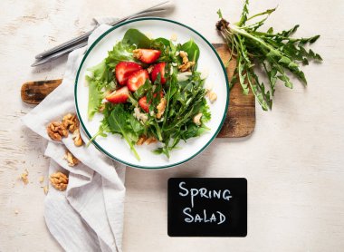 Beyaz arka planda çilekli karahindiba salatası ve ceviz tabağı..