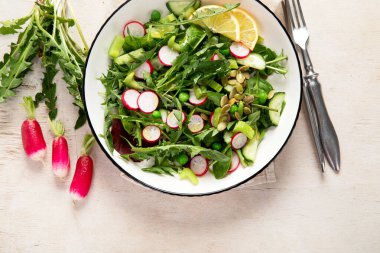 Karahindiba yapraklı bahar vejetaryen salatası, turp, ahşap kaplama salatalık. Üst görünüm