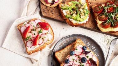 Hafif arka planda bir sürü vejetaryen sandviçi. Peynir, avokado, roka, domates ve humus ile sağlıklı tost. Sağlıklı beslenme. Üst görünüm.