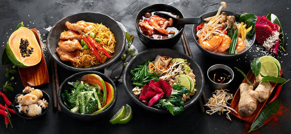 Ассорти тайской еды. Знаменитые блюда кухни на столе на темном фоне. Вид сверху. Концепция тайского ресторана. Панорама.