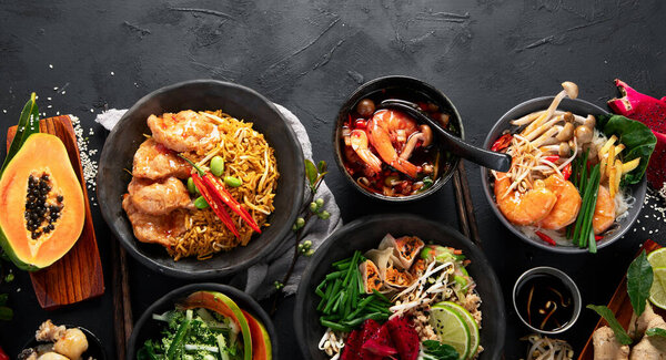 Ассорти тайской еды. Знаменитые блюда кухни на столе на темном фоне. Вид сверху. Концепция тайского ресторана. Панорама с копировальным пространством.