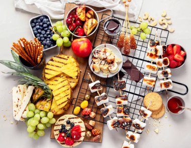 Izgara tatlı ve meyve çeşitleri. Yaz bbq masası. Ananas, şeftali, muz, marşmelov, çilek, hafif arkaplanda yabanmersini. Üst görünüm