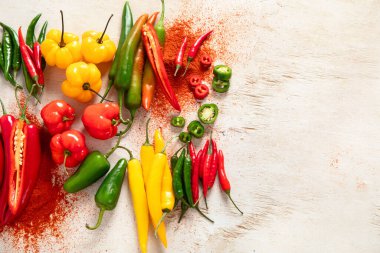 Hafif ahşap arka planda renkli çiğ biberler. Lezzetli sebze konsepti. Üst görünüm, alanı kopyala