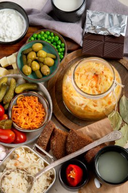 Probiotic food concept. Cabbage in jar, pickle, carrot on light wooden background. Top view clipart