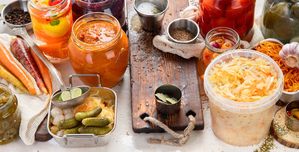 Ферментированные продукты на деревянном фоне. Маринованные овощи в банках. Вид сверху