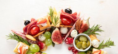 Noel için atıştırmalık çelenk. Sebzeli peynirli kanepeler ve beyaz arka planda salam. Noel çelengi. Üst Manzara. Panorama.