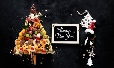 Christmas tree with sweets and cookies decoration on dark background. Holiday food. Top view.