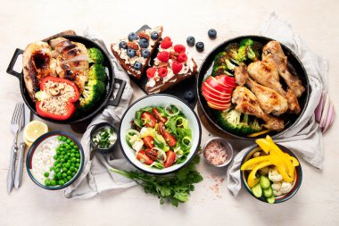 Yeşil sebzeli, tavuklu ve arka planda taze salatalı çeşitli tabak ve kaseler. Sağlıklı gıda konsepti. Üst görünüm.