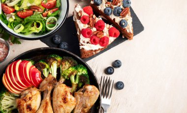 Yeşil sebzeli, tavuklu ve arka planda taze salatalı çeşitli tabak ve kaseler. Sağlıklı gıda konsepti. Üst Manzara. Boşluğu kopyala.