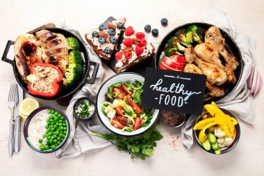 Yeşil sebzeli, tavuklu ve arka planda taze salatalı çeşitli tabak ve kaseler. Sağlıklı gıda konsepti. Üst görünüm.