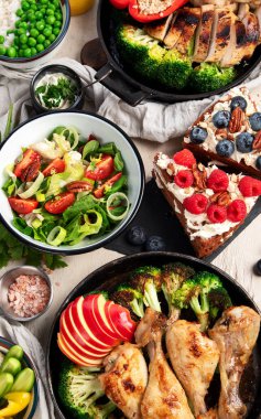 Yeşil sebzeli, tavuklu ve arka planda taze salatalı çeşitli tabak ve kaseler. Sağlıklı gıda konsepti. Üst görünüm.