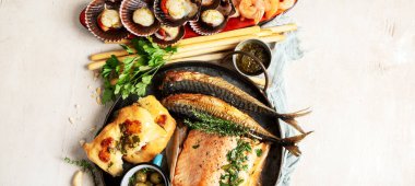 Çeşitli Akdeniz yemekleri - balık, karides, deniz ürünleri, ravioli, beyaz arka planda sebzeler. Üst görünüm. 