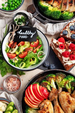 Yeşil sebzeli, tavuklu ve arka planda taze salatalı çeşitli tabak ve kaseler. Sağlıklı gıda konsepti. Üst görünüm.