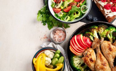 Yeşil sebzeli, tavuklu ve arka planda taze salatalı çeşitli tabak ve kaseler. Sağlıklı gıda konsepti. Üst Manzara. Boşluğu kopyala.