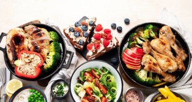 Yeşil sebzeli, tavuklu ve arka planda taze salatalı çeşitli tabak ve kaseler. Sağlıklı gıda konsepti. Üst Manzara. Boşluğu kopyala.