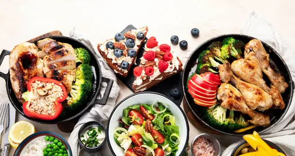 Yeşil sebzeli, tavuklu ve arka planda taze salatalı çeşitli tabak ve kaseler. Sağlıklı gıda konsepti. Üst Manzara. Boşluğu kopyala.