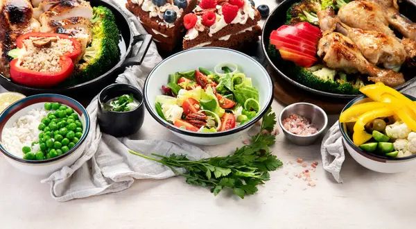 Yeşil sebzeli, tavuklu ve arka planda taze salatalı çeşitli tabak ve kaseler. Sağlıklı gıda konsepti. Üst Manzara. Boşluğu kopyala.