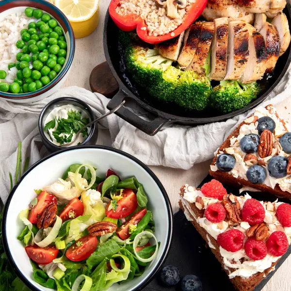 Yeşil sebzeli, tavuklu ve arka planda taze salatalı çeşitli tabak ve kaseler. Sağlıklı gıda konsepti. Üst görünüm.