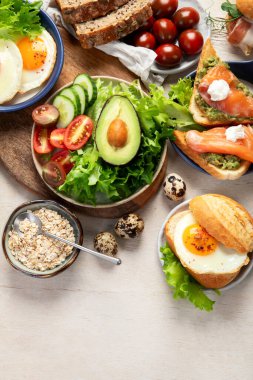 Kahvaltı masası. Portakal suyu, meyve, sebze, müsli, somon balığı, yumurta ve kruvasanın olduğu masaya yayılmış sağlıklı bir kahvaltı. Üst Manzara. Boşluğu kopyala.