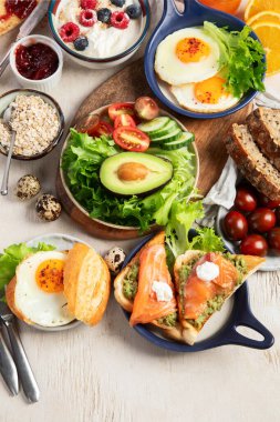 Kahvaltı masası. Portakal suyu, meyve, sebze, müsli, somon balığı, yumurta ve kruvasanın olduğu masaya yayılmış sağlıklı bir kahvaltı. Üst Manzara. Boşluğu kopyala.