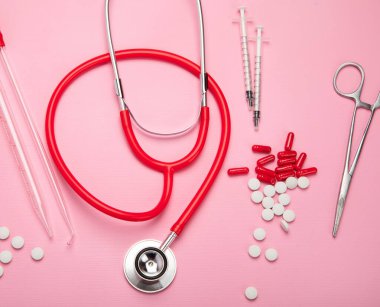 Çeşitli tıbbi ekipmanlar, pipetler, ilaçlar, haplar, kapsüller, pembe arka planda sprey. Üst görünüm