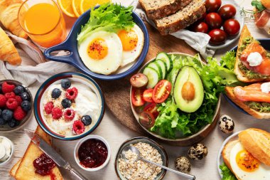 Kahvaltı masası. Portakal suyu, meyve, sebze, müsli, somon balığı, yumurta ve kruvasanın olduğu masaya yayılmış sağlıklı bir kahvaltı. Üst görünüm. 