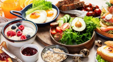 Kahvaltı masası. Portakal suyu, meyve, sebze, müsli, somon balığı, yumurta ve kruvasanın olduğu masaya yayılmış sağlıklı bir kahvaltı. Üst görünüm. 