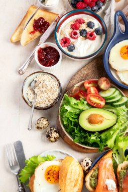 Kahvaltı masası. Portakal suyu, meyve, sebze, müsli, somon balığı, yumurta ve kruvasanın olduğu masaya yayılmış sağlıklı bir kahvaltı. Üst görünüm. 