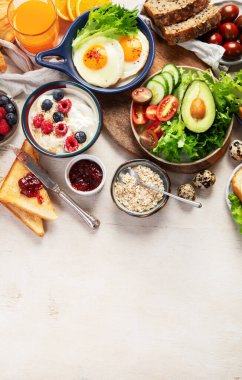 Kahvaltı masası. Portakal suyu, meyve, sebze, müsli, somon balığı, yumurta ve kruvasanın olduğu masaya yayılmış sağlıklı bir kahvaltı. Üst Manzara. Boşluğu kopyala.