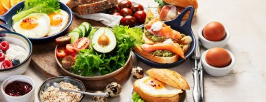 Kahvaltı masası. Portakal suyu, meyve, sebze, müsli, somon balığı, yumurta ve kruvasanın olduğu masaya yayılmış sağlıklı bir kahvaltı. Üst Manzara. Kopyalama alanı olan Panorama.