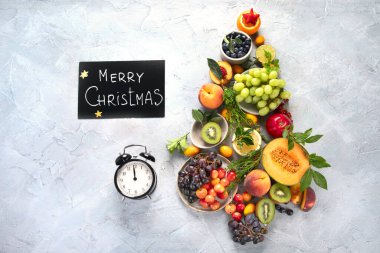 Açık gri arka planda meyvelerden yapılmış Noel ağacı. Yeni yıl tatili konsepti. Üst görünüm, düz görünüm, kopyalama alanı
