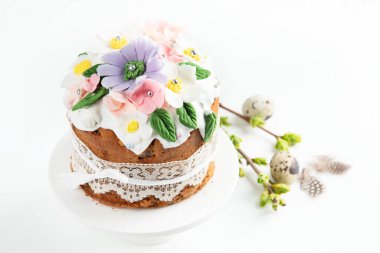 Paskalya pastası, tavşan kulaklarıyla süslenmiş tatlı ekmek ve pembe arka planda bahar çiçekleri. Üst görünüm.