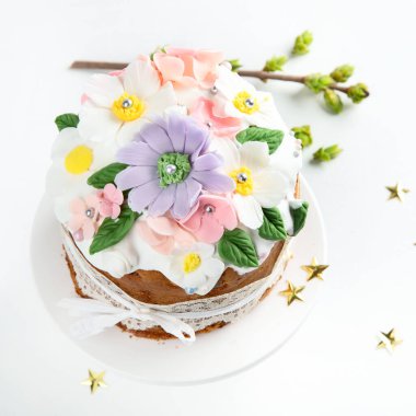 Paskalya pastası, tavşan kulaklarıyla süslenmiş tatlı ekmek ve pembe arka planda bahar çiçekleri. Üst görünüm.