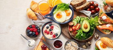 Kahvaltı masası. Portakal suyu, meyve, sebze, müsli, somon balığı, yumurta ve kruvasanın olduğu masaya yayılmış sağlıklı bir kahvaltı. Üst Manzara. Kopyalama alanı olan Panorama.