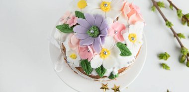 Paskalya pastası, tavşan kulaklarıyla süslenmiş tatlı ekmek ve pembe arka planda bahar çiçekleri. Üst Manzara. Panorama.