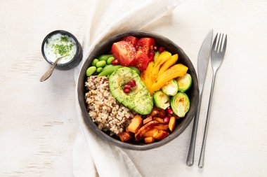 İçinde kinoa, avokado, domates, nohut ve brokoli olan Budha kasesi. Arka planda Vegan Budha kasesi, üst manzara.