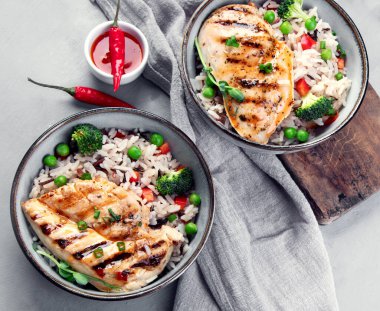 Sebzeli ızgara tavuk ve gri arka planda pilav. Sağlıklı beslenme konsepti. Üst görünüm, düz görünüm, kopyalama alanı