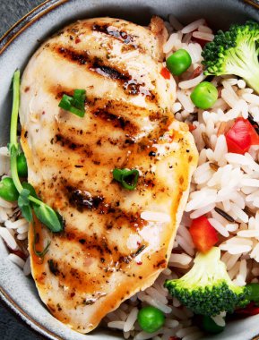 Sebzeli ızgara tavuk ve gri arka planda pilav. Sağlıklı beslenme konsepti. Üst görünüm, düz görünüm, kopyalama alanı