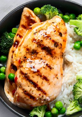 Yeşil sebzeli ızgara tavuk ve gri arka planda pirinç. Sağlıklı beslenme konsepti. Üst manzara, düz uzanma