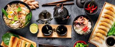 Karanlık arka planda çeşitli malzemeli Asya yemekleri. Panorama. Pankart