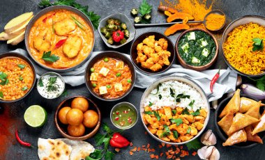 Hint mutfağı tabakları. Köri, tereyağlı tavuk, pilav, mercimek, paneer, samosa, baharatlar. Hint yemekli kase ve tabaklar. Üst görünüm..